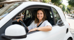 אישה מחייכת ברכב לאחר שביצעה השוואת רכבי מיני 2025 ורכשה שירותי דרך בכל הארץ.