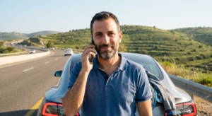 נהג רגוע לצד רכבו לאחר שקיבל שירות בנושא אסטרטגיית החשמל של טויוטה ומאזדה בכל הארץ.